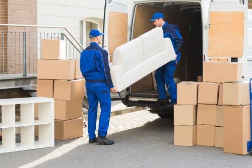 Removalists navigating large furniture through a narrow doorway
